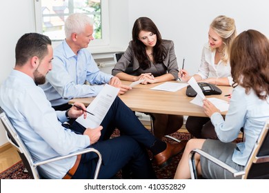 Lawyers Having Team Meeting In Law Firm Reading Documents