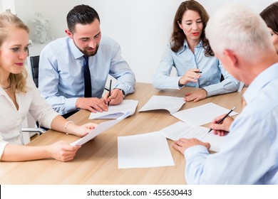 Lawyers Having Team Meeting In Law Firm Reading Documents And Negotiating Agreements