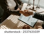 Lawyers shaking hands after signing a contract in a law office, with a gavel and legal scales in the background