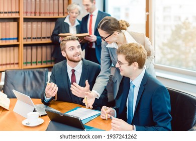 Lawyers In Their Law Firm Working On Computer With Books In Background