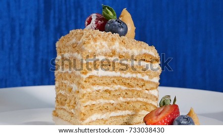 Layer cake with cuted strawberry and blueberries on plate. Summer berry cake. Piece of Multi-layered Berry and Pistachio Mousse Cake