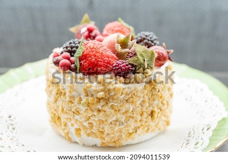 layer cake Napoleon with berries assortment on a plate of the windowshop. Sweet dessert for celebration.