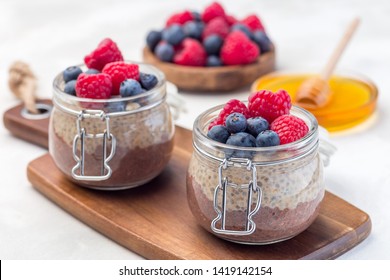 Layered Chocolate And Peanut Butter Chia Seed Pudding In A Jar, Garnished With Raspberry And Blueberry, Horizontal