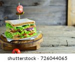 Layered club sandwich entirely on a wooden board, old wooden background copy space