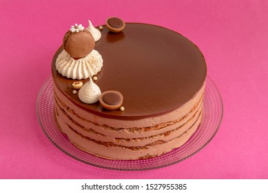 layered cocoa cake on pink background with toffifee and meringue