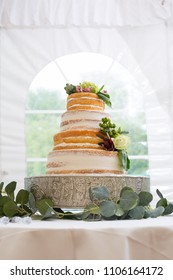 Layered Delicious Wedding Cake Decorated With Floral Pieces Inside White Tent Venue.