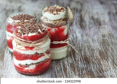Layered dessert with fruits, nuts and cream cheese in glass jar, selective focus