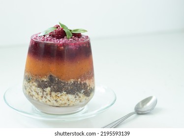 Layered Plant-based Chia Pudding Made With Fresh Fruit, Veggies, Oats, Chia Seeds, And Nuts In A Glass With Spoon On White. A Closeup.