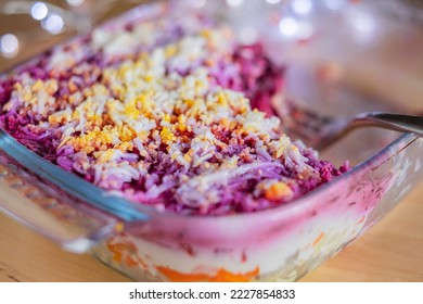 Layered salad herring under fur coat on table. Portion of traditional russian salad with herring, beet ,carrot and egg