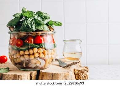 A layered salad in a jar featuring red onion, chickpeas, cucumber, tomatoes, grilled chicken, and baby spinach. A healthy, colorful, and convenient meal, perfect for on-the-go lunches. Selective focus - Powered by Shutterstock