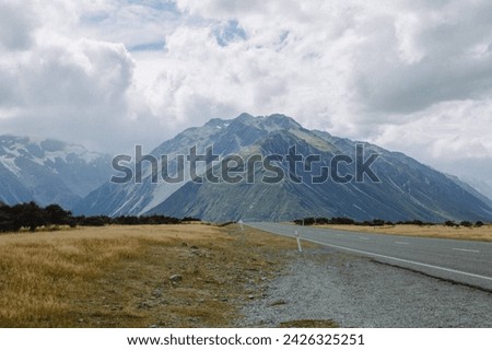 Layered storm cloud covered sky above beautiful natural textured snow capped mountain peaks from scenic road side in rural New Zealand South Island