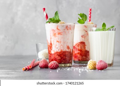 Layered strawberry and raspberry smoothie or milkshake in glasses decorated with mint, raspberry and coconut flakes. Healthy food for breakfast or snack. - Powered by Shutterstock