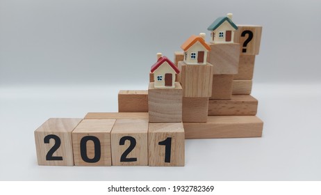 Layering Stacks Of Wooden Blocks With Miniature Houses On Top To Represent The 2021 Housing Market