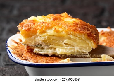 Layers of Creamy Gratin dauphinois potato with melted cheese on wooden serving spatula - Shutterstock ID 2195018859