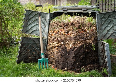 Layers of rotting compost in plastic composter bin in garden