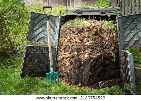 Layers of rotting compost in plastic composter bin in garden