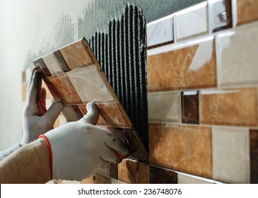 Laying Ceramic Tiles. Tiler placing ceramic wall tile in position over adhesive