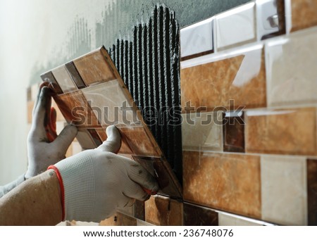 Laying Ceramic Tiles. Tiler placing ceramic wall tile in position over adhesive