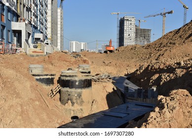 Laying Concrete Manholes And Heating Drain Pipes And For Stormwater System In Trench At Construction Site. Sewerage Manhole And Pipes Line Under Construction.  Chambers And Pump Station