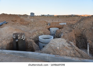 Laying Concrete Manholes And Heating Drain Pipes And For Stormwater System In Trench At Construction Site. Sewerage Manhole And Pipes Line Under Construction.  Chambers And Pump Station