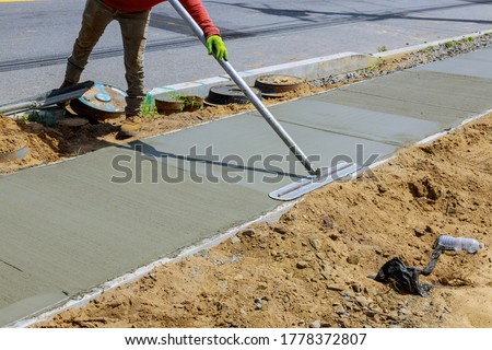 Laying down new sidewalk in wet concrete on freshly poured sidewalks