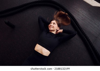 Laying Down And Taking A Break. Top View. Young Beautiful Woman In Sportive Clothes Have Fitness Day In The Gym.