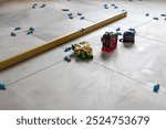 Laying floor tiles. Linear level. Green hand gloves