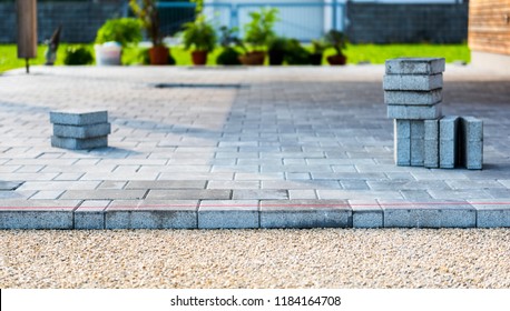Laying gray concrete paving slabs in house courtyard driveway patio. Professional workers bricklayers are installing new tiles or slabs for driveway, sidewalk or patio on leveled sand foundation base. - Shutterstock ID 1184164708