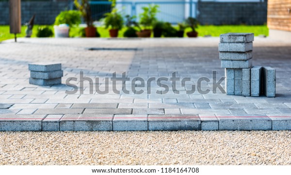 Laying gray concrete paving slabs in house\
courtyard driveway patio. Professional workers bricklayers are\
installing new tiles or slabs for driveway, sidewalk or patio on\
leveled sand foundation\
base.
