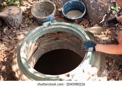 Laying A Hatch On A Sewer Well. The Man Strengthens The Neck Of The Septic Tank.