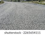 laying a new road, filled with gravel and crushed stone. macadam during road construction. Granite gravel of macadam, rock gray crushed for construction on the ground. background. Gravel fragments.