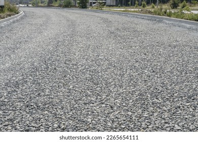 laying a new road, filled with gravel and crushed stone. macadam during road construction. Granite gravel of macadam, rock gray crushed for construction on the ground. background. Gravel fragments.