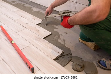 Laying Terracotta In The Bathroom. Builder During Work. Adhesive For Ceramic Tiles.