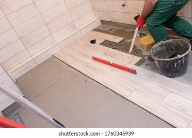 Laying Terracotta In The Bathroom. Builder During Work. Adhesive For Ceramic Tiles.