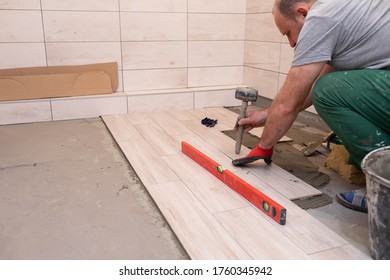 Laying Terracotta In The Bathroom. Builder During Work. Adhesive For Ceramic Tiles.