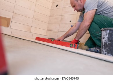 Laying Terracotta In The Bathroom. Builder During Work. Adhesive For Ceramic Tiles.