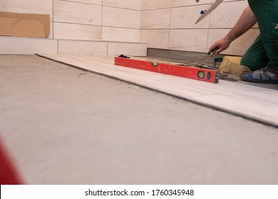 Laying Terracotta In The Bathroom. Builder During Work. Adhesive For Ceramic Tiles.