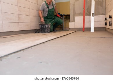 Laying Terracotta In The Bathroom. Builder During Work. Adhesive For Ceramic Tiles.