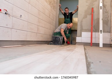 Laying Terracotta In The Bathroom. Builder During Work. Adhesive For Ceramic Tiles.