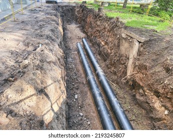 Laying Of Underground Communications For Residential Buildings. Black Plumbing Pipes Made Of Durable And Reliable Material Are Buried Deep In An Earthen Ditch.