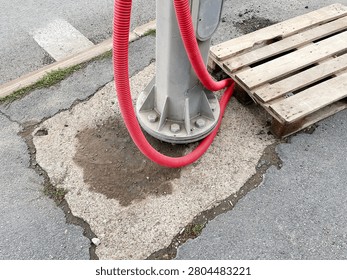 Laying underground utility cables using red flexible corrugated conduits near a street light pole during sidewalk repairs.