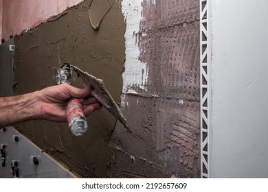 Laying Wall Ceramic Tile. Renovating The Wall. Construction Worker Laying Tile Over Concrete Wall Using Tile Levelers, Notched Trowels And Tile Glue.