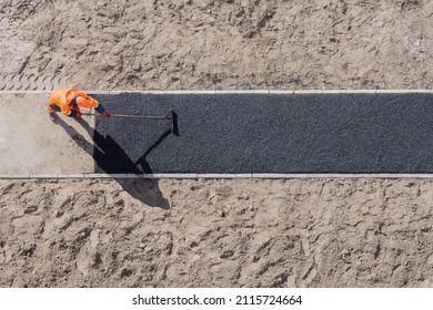 Laying worker new asphalt paving road construction site work pathway. New road construction worker laying asphalt surface on walkway work path. Sidewalk construction asphalt work tarmac road worker - Shutterstock ID 2115724664