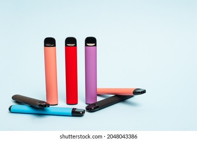 Layout of colorful disposable electronic cigarettes on a light blue background. The concept of modern smoking, vaping and nicotine. 