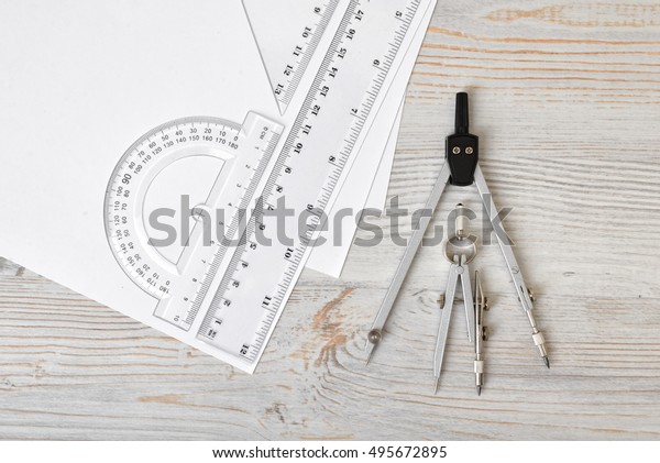 Layout with compass, protractor and centimeter\
ruler on wooden surface in top view. Workplace of draftsman,\
architect, constructor or designer. Engineering work. Measurement.\
Tools for drawing.
