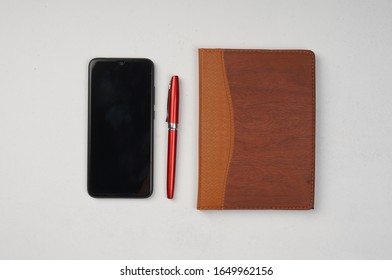The layout is flat with a white background including: pen, Note Book and Smartphone. See from above