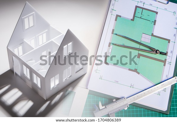 Layout of the house next to the drawings. Concept -\
work in an architectural bureau. Concept - order for a cottage\
project. Dividers lies on the construction drawings. Layout of the\
house top view.