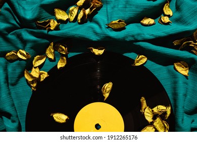 Layout of LP vinyl record on a cyan silk or saten fabric with yellow rose patels on it.  Old vintage record. - Shutterstock ID 1912265176