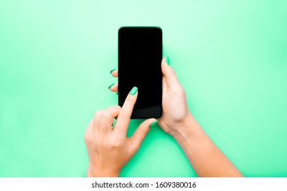 The Layout Of The Phone. The Girl Flips Through The Pages. Swipe Your Finger Across The Screen. Background Mint Color Under The Color Of Nails. Pantone 2020. Neo Mint Color. Flat Lay.