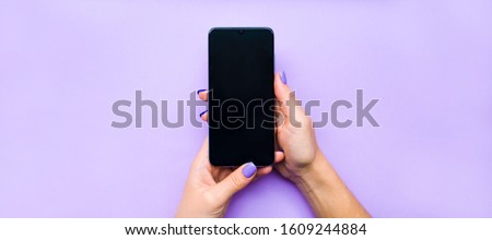 The layout of the phone. The girl holds the phone with both hands. Background lilac under the color of nails. A beautiful manicure. Flat lay.